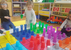 dzieci układają kubeczki na macie zgodnie z kolorem